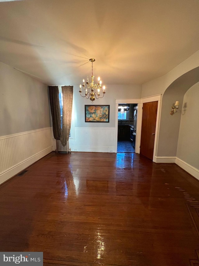 unfurnished dining area featuring radiator, dark hardwood / wood-style flooring, and an inviting chandelier