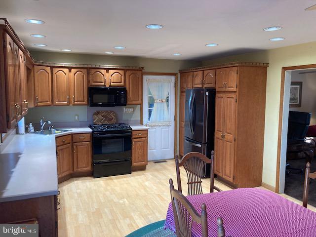 kitchen with sink, light hardwood / wood-style floors, and black appliances