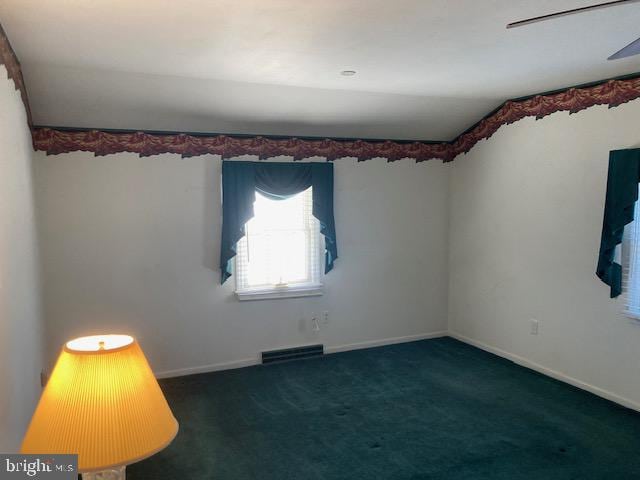 empty room with vaulted ceiling, dark carpet, and ceiling fan