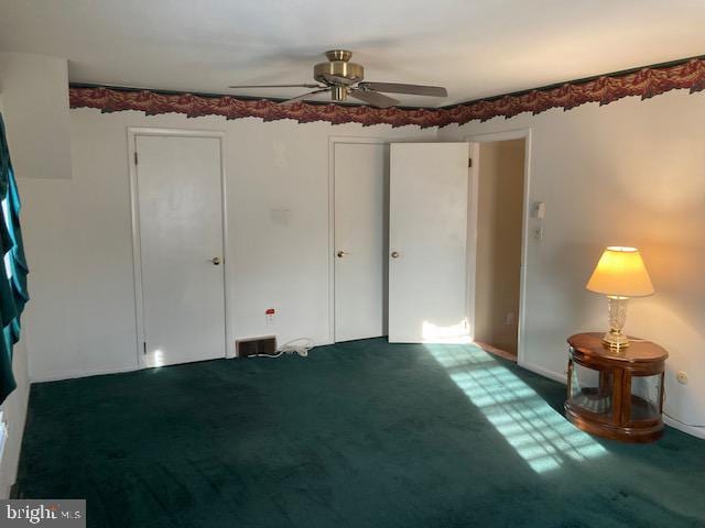 unfurnished bedroom featuring dark colored carpet and ceiling fan