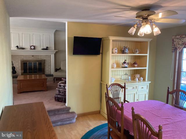 dining space featuring ceiling fan and a fireplace