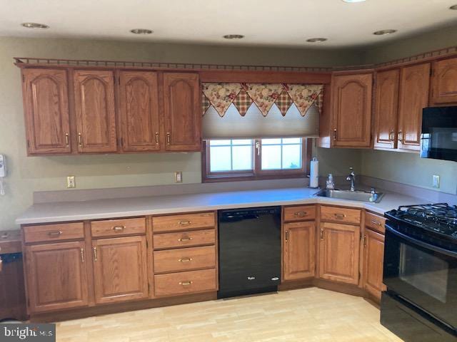 kitchen with sink, light hardwood / wood-style flooring, and black appliances