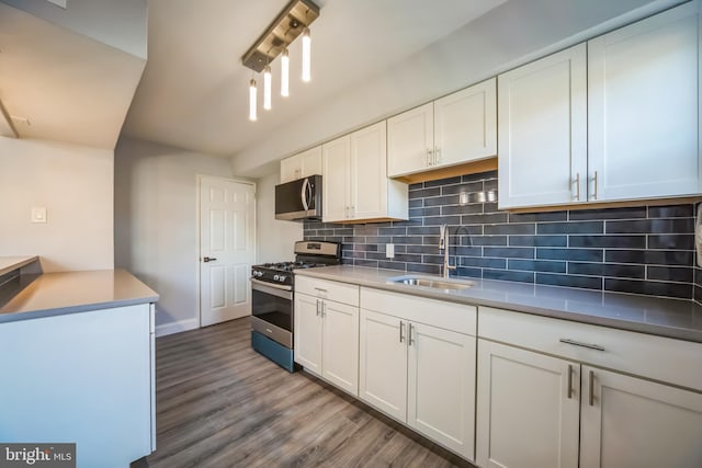 kitchen with white cabinets, sink, hardwood / wood-style flooring, appliances with stainless steel finishes, and tasteful backsplash