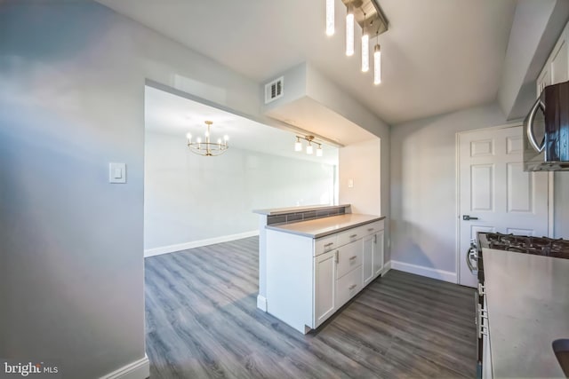 kitchen with kitchen peninsula, stainless steel appliances, white cabinetry, and dark wood-type flooring