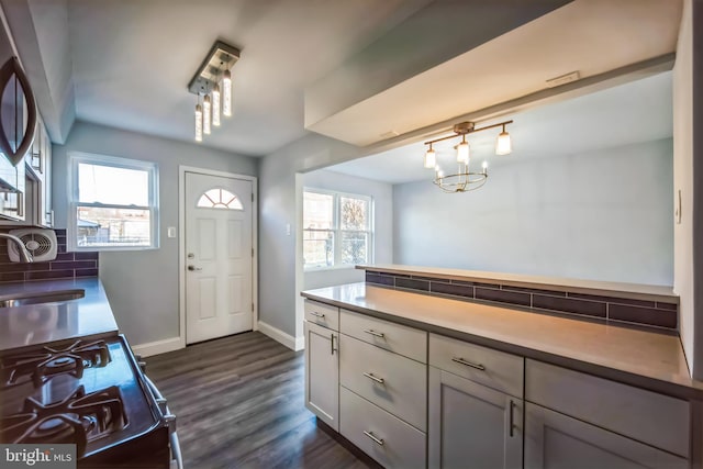 kitchen featuring backsplash, gas range, dark hardwood / wood-style flooring, and a healthy amount of sunlight