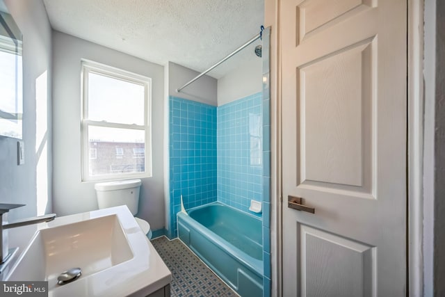 full bathroom featuring toilet, vanity, a textured ceiling, and tiled shower / bath