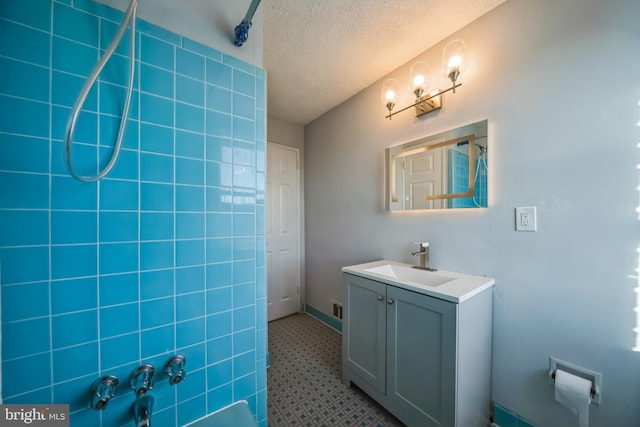 bathroom with vanity, a textured ceiling, and walk in shower