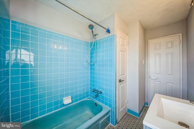 bathroom featuring a textured ceiling, tiled shower / bath, and sink