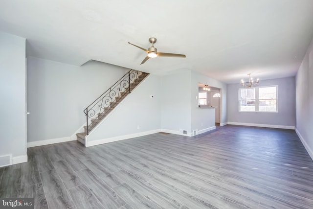 unfurnished living room featuring ceiling fan with notable chandelier and hardwood / wood-style flooring