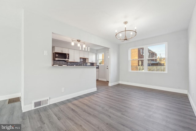 unfurnished living room with hardwood / wood-style flooring and a chandelier