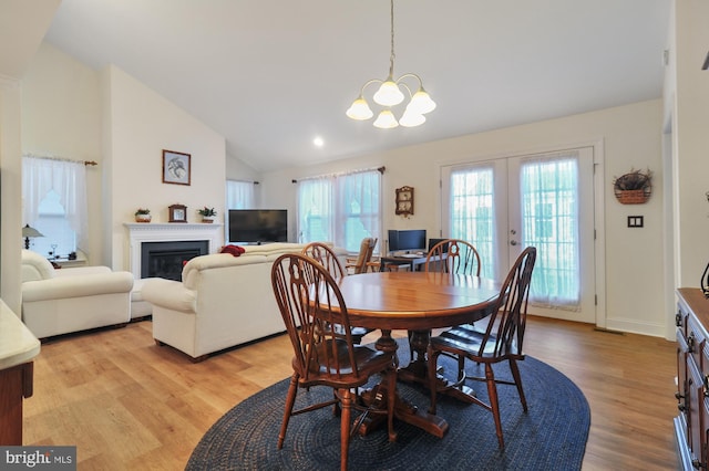 dining room with an inviting chandelier, light wood-type flooring, high vaulted ceiling, and french doors