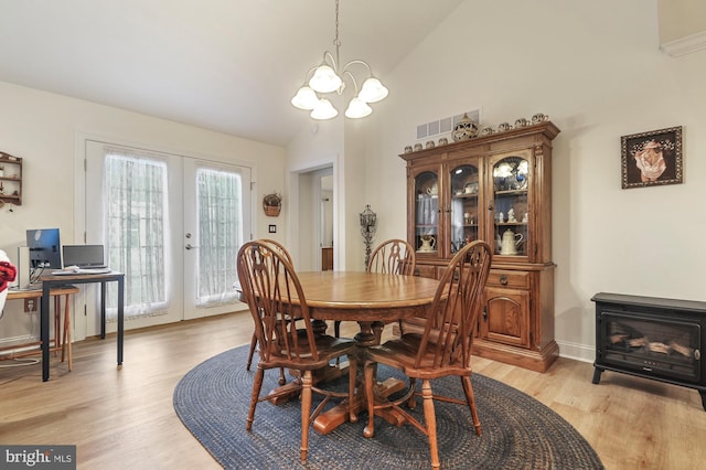 dining room with french doors, light wood-type flooring, an inviting chandelier, and lofted ceiling