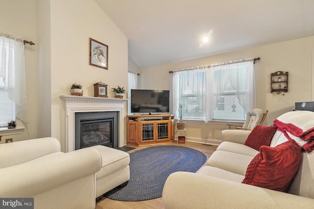 living room featuring plenty of natural light, light wood-type flooring, and vaulted ceiling