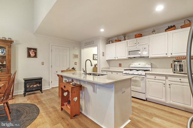 kitchen featuring light wood-type flooring, white appliances, a kitchen island with sink, sink, and white cabinets