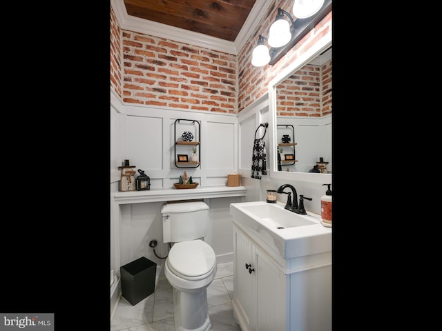 bathroom with vanity, toilet, crown molding, and brick wall