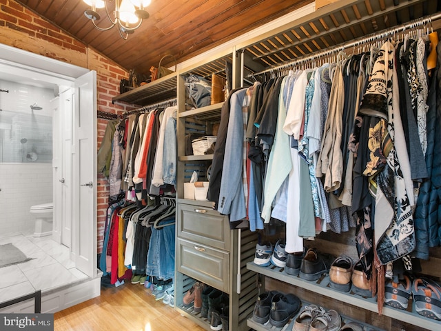 spacious closet with a chandelier, hardwood / wood-style floors, and vaulted ceiling