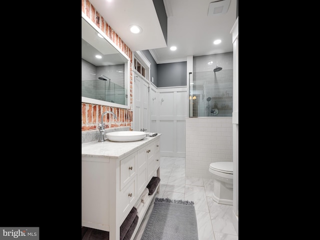 bathroom with crown molding, toilet, vanity, and tiled shower