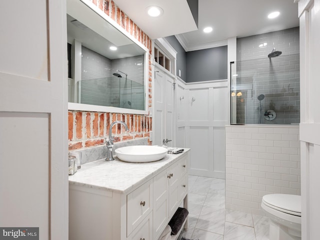 bathroom featuring crown molding, toilet, vanity, and tiled shower