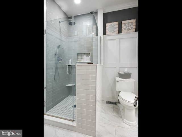 bathroom featuring toilet, an enclosed shower, and tile walls