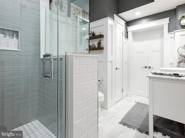 bathroom with a shower with door, vanity, and toilet