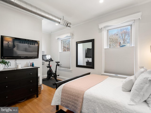 bedroom with multiple windows, light hardwood / wood-style flooring, and ornamental molding