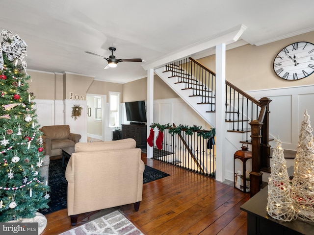 living room with dark hardwood / wood-style flooring, ceiling fan, and ornamental molding