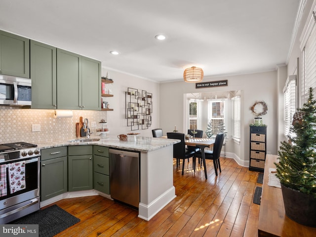 kitchen with stainless steel appliances, crown molding, hardwood / wood-style flooring, and green cabinets