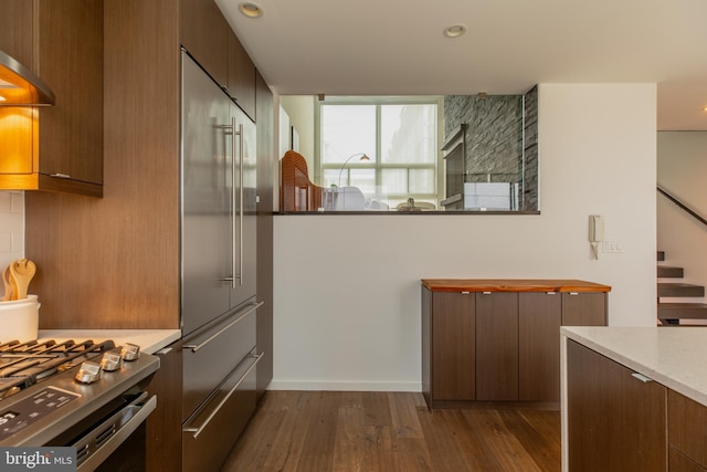 kitchen featuring tasteful backsplash, dark hardwood / wood-style flooring, wall chimney exhaust hood, and stainless steel appliances