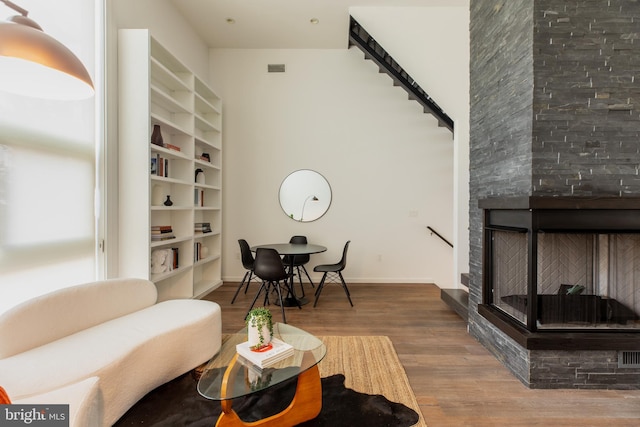 living room featuring wood-type flooring, a fireplace, and built in features