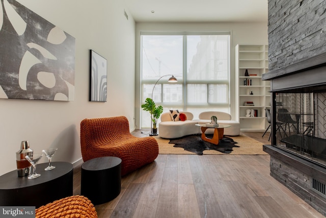 living area with light hardwood / wood-style flooring and a stone fireplace