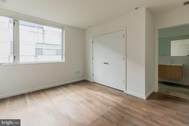 unfurnished bedroom featuring sink, light wood-type flooring, and a closet