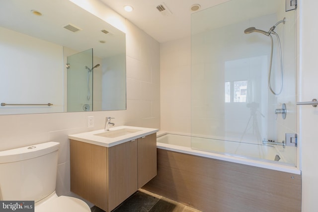 full bathroom with tile walls, toilet, vanity, and tiled shower / bath