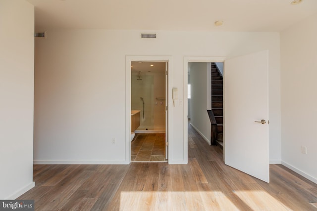 unfurnished bedroom featuring ensuite bath and hardwood / wood-style flooring