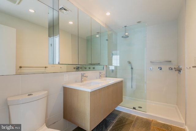 bathroom featuring toilet, tiled shower, tile walls, and vanity