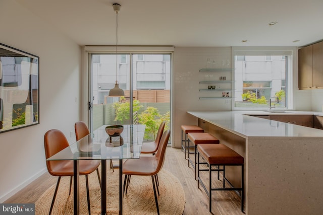 dining space with light wood-type flooring and sink