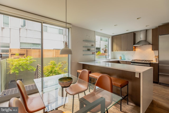 kitchen featuring appliances with stainless steel finishes, decorative backsplash, plenty of natural light, and wall chimney exhaust hood