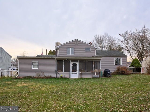 rear view of house featuring a sunroom and a yard