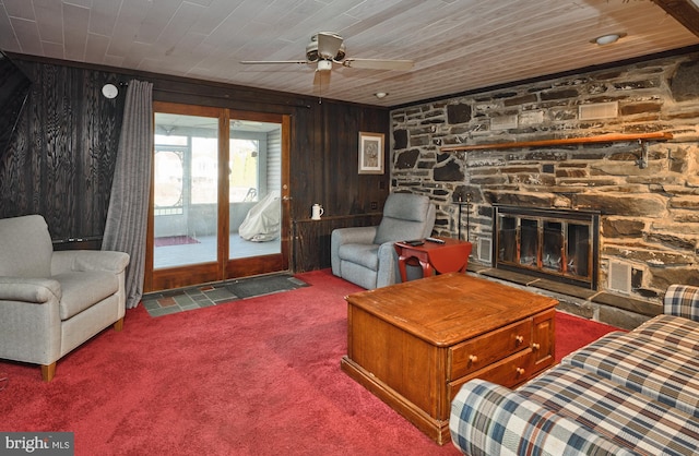 living room with wood ceiling, ceiling fan, a fireplace, carpet floors, and wood walls