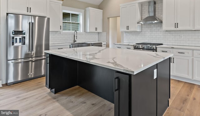 kitchen featuring a kitchen island, sink, white cabinets, high end appliances, and wall chimney exhaust hood