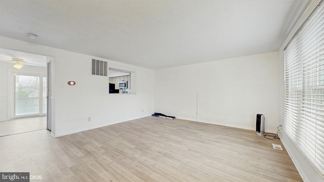 empty room featuring a textured ceiling, light hardwood / wood-style flooring, and ceiling fan