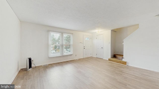 interior space with a textured ceiling and light hardwood / wood-style floors