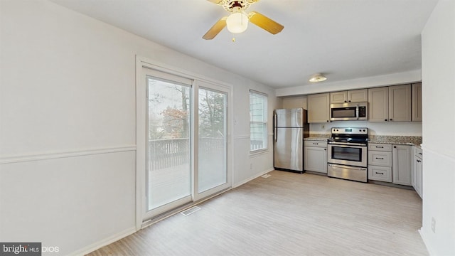 kitchen with gray cabinets, light stone counters, light wood-type flooring, and appliances with stainless steel finishes