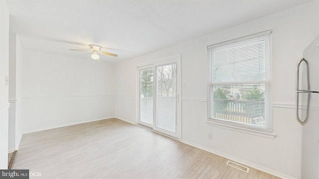 empty room featuring ceiling fan, plenty of natural light, a textured ceiling, and light wood-type flooring