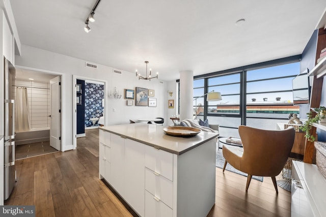 kitchen featuring pendant lighting, white cabinets, a center island, a wall of windows, and dark hardwood / wood-style floors