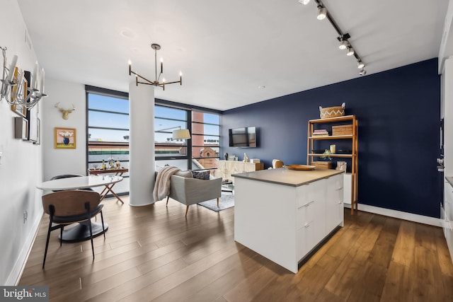 kitchen featuring white cabinets, a kitchen island, decorative light fixtures, an inviting chandelier, and dark hardwood / wood-style floors