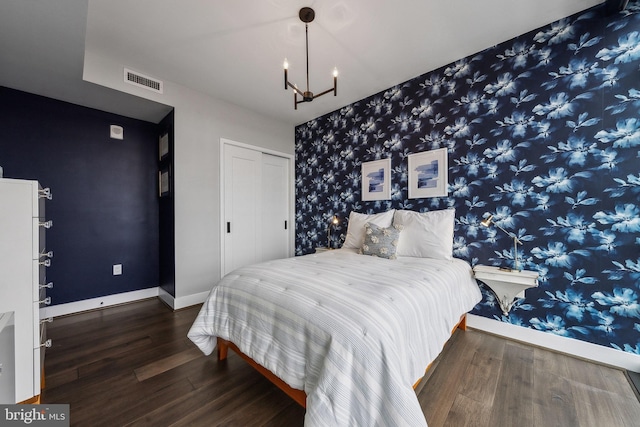 bedroom featuring a closet, dark hardwood / wood-style flooring, and an inviting chandelier