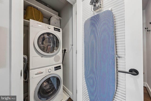 laundry area featuring hardwood / wood-style floors and stacked washing maching and dryer