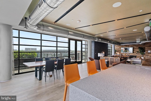 dining room with light hardwood / wood-style floors, a wealth of natural light, and a wall of windows