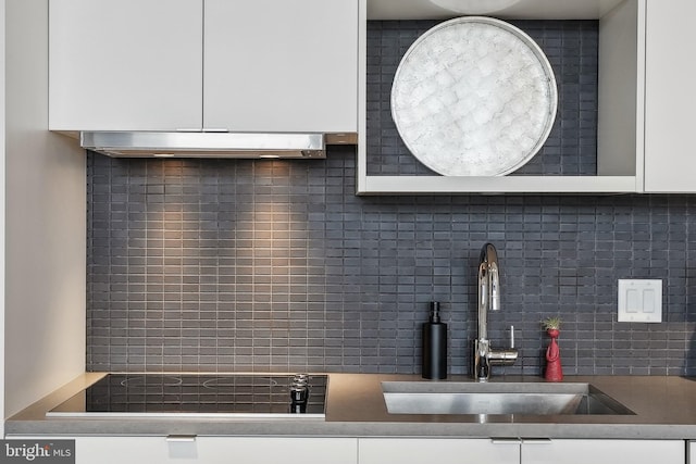 kitchen featuring sink, black electric cooktop, tasteful backsplash, and white cabinetry