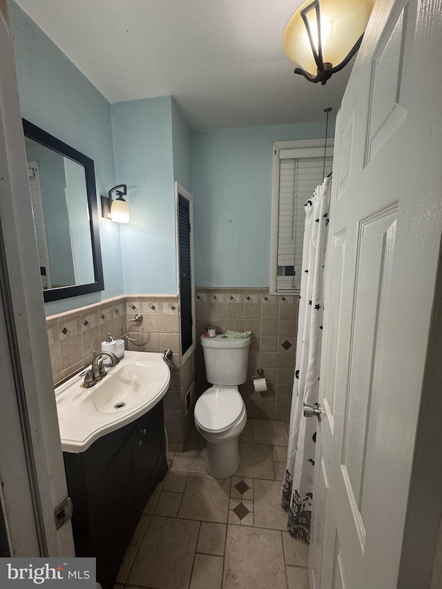 bathroom featuring tile patterned floors, vanity, toilet, and tile walls